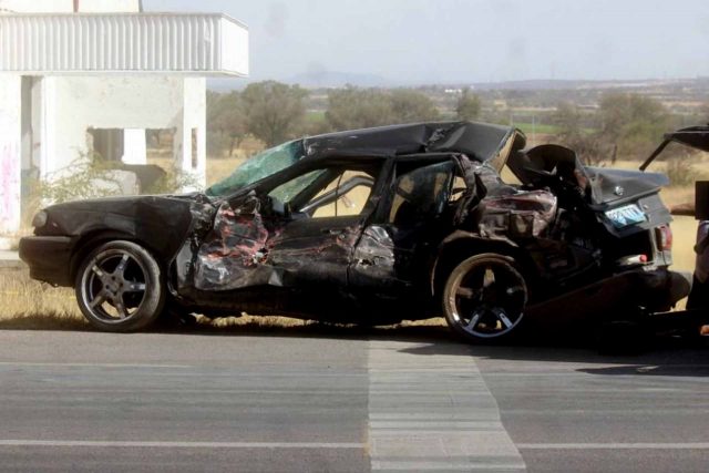 Sentra negro que fue colisionado por un trailer