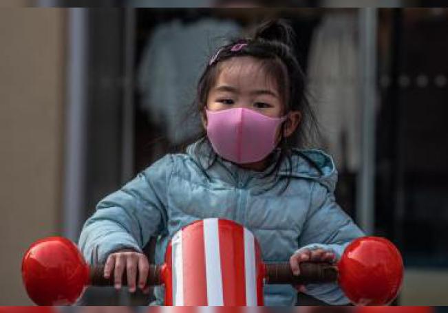 Una niña con una mascarilla facial sanitaria juega en un parque de una desértica área comercial en Solana, este miércoles en Pekín (China). EFE/ Roman Pilipey