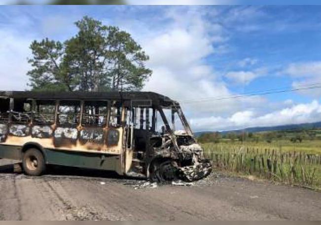 Vista general este lunes de un autobús incendiado para bloquear el acceso a los poblados de Tocombo y Los Reyes, en occidental estado de Michoacán