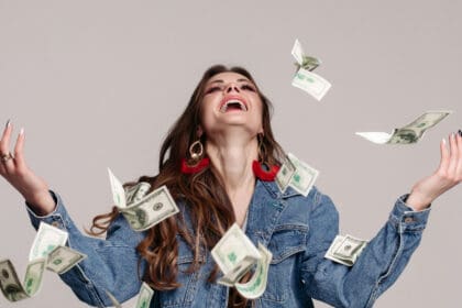 chica riendo feliz chaqueta mezclilla billetes voladores alrededor scaled e1677509105432