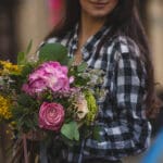 woman holding bouquet mixed flowers shades pink hand street view