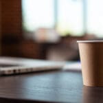 close up disposable coffee cup laptop office desk startup space hot beverage table empty business workplace drink plastic cup furniture computer